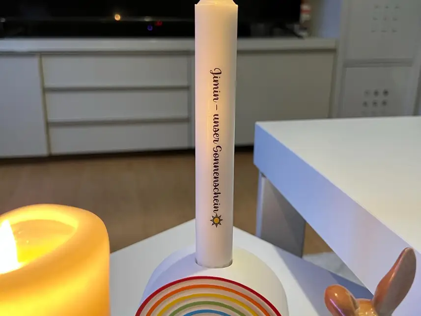 Brennende Stabkerze im Regenbogen-Kerzenhalter