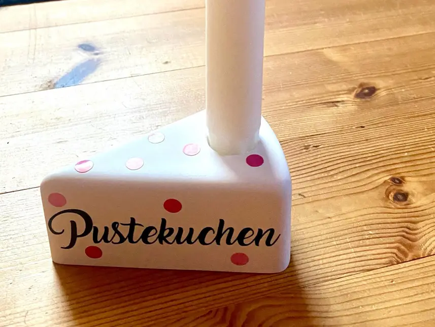 Kerzenhalter in Form eines Tortenstücks mit dem Schriftzug Pustekuchen