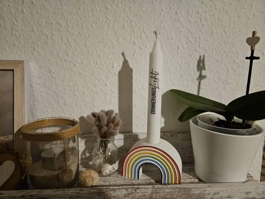 Regenbogen-Kerzenhalter mit Stabkerze auf einer Fensterbank
