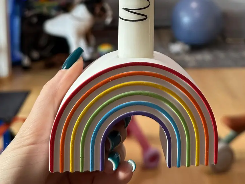 Regenbogen-Kerzenhalter mit Stabkerze in einer Hand