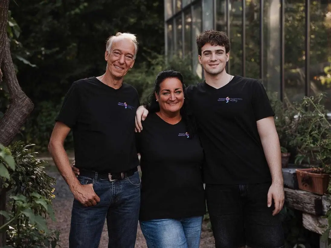 Drei Personen in schwarzen T-Shirts mit einem kleinen Logo auf der Brust