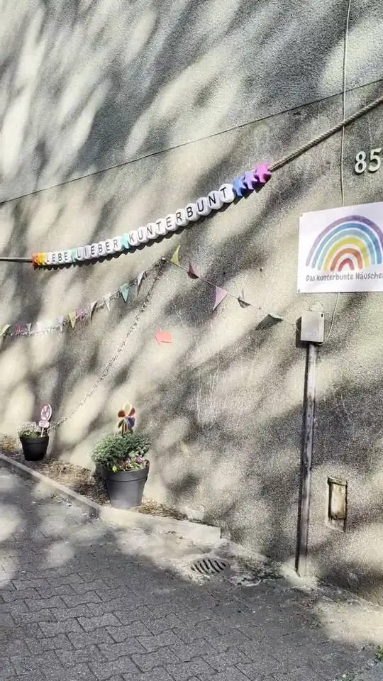 Hauswand mit der Girlande Lebe Lieber Kunterbunt, hier geht es entlang zum Häuschen
