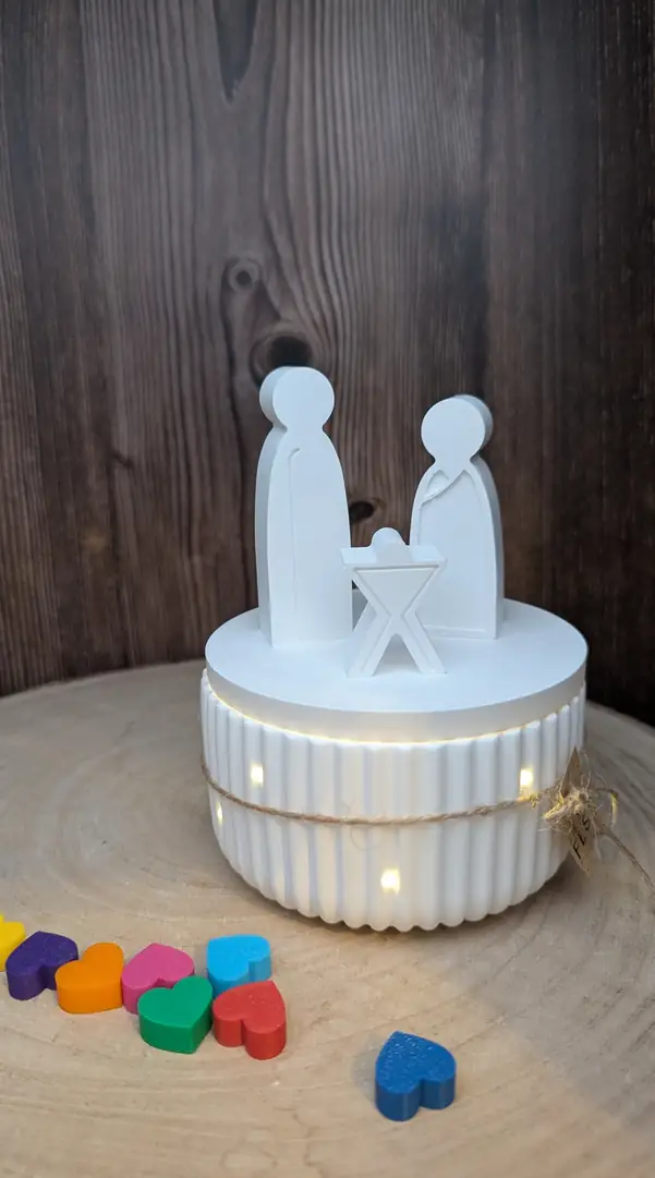 Weiße Krippenfiguren auf einem beleuchteten Sockel