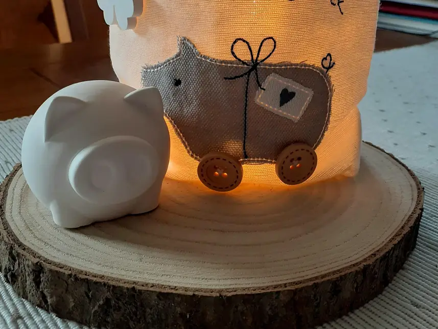 Weißes Glücksschwein vor einem Windlicht
