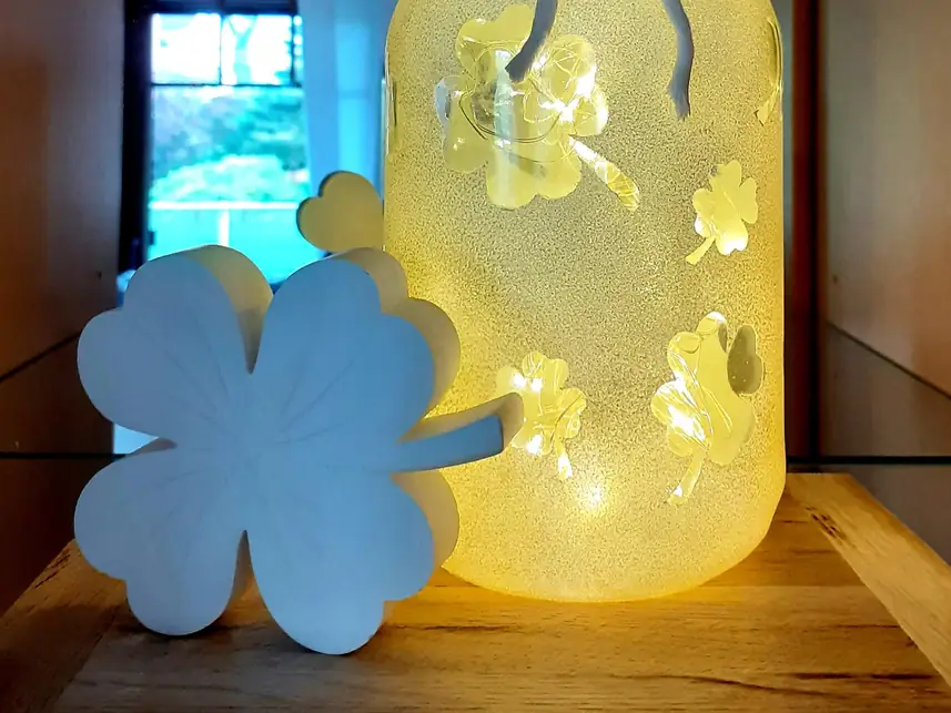 Weißes Kleeblatt vor einem leuchtenden Glas